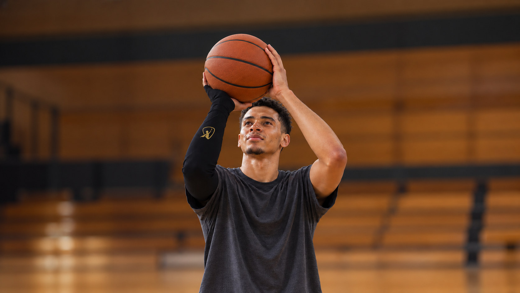 A basketball player at his free-throw set point, the black Betta sleeve with its gold Betta logo on his shooting arm