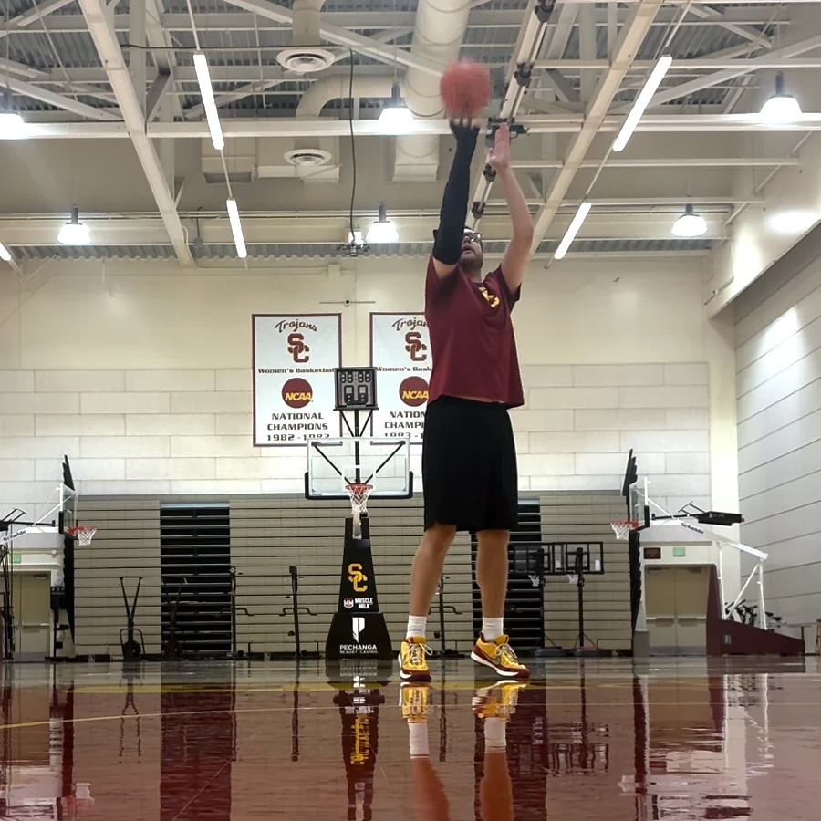 A player at the free-throw line in a gym, the ball just off his fingertips, the black Betta sleeve on his shooting arm. Marked: Counted.
